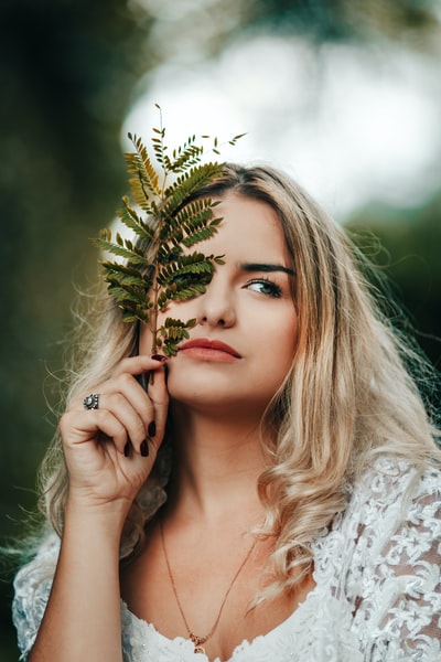 woman in white floral shirt holding green plant